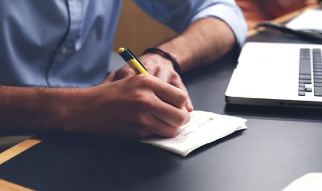 man writing on a pad of paper